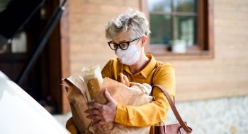 senior-woman-with-face-mask-outdoors-with-shopping-P4BEJZG.jpg