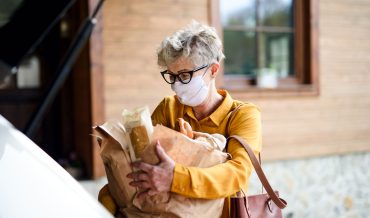 senior-woman-with-face-mask-outdoors-with-shopping-P4BEJZG.jpg